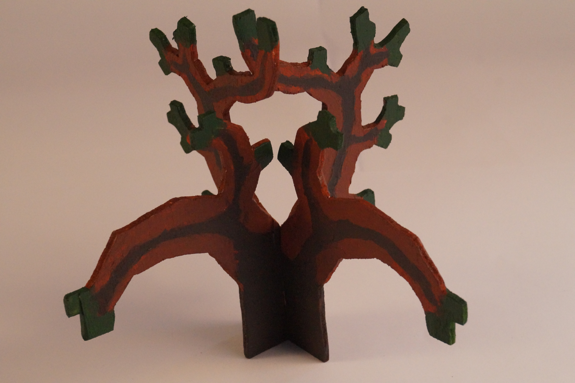 Two colored pieces of plywood, each showing a cut-out of a Pythagoras' tree. They are stuck together at a 90-degree angle to form a 3D tree.